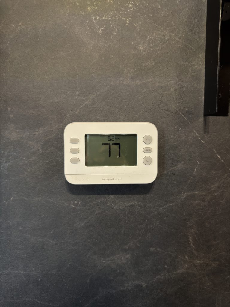 Digital wall thermostat mounted on a gray interior wall in Keulen Camp #132.