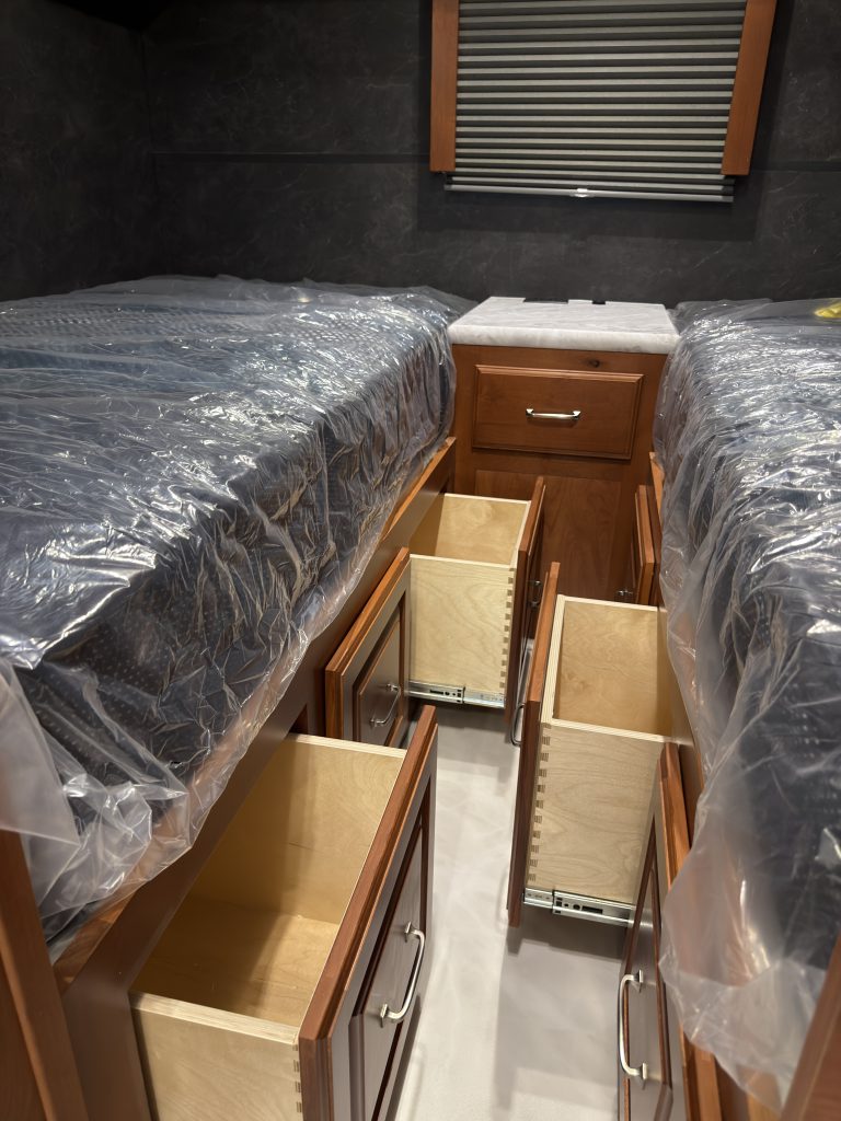 Multiple drawers extended from the central nightstand and sleeping-area cabinetry in Keulen Camp #132.