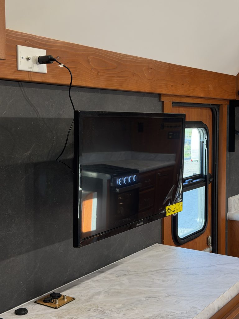 Wall-mounted television above the media center near the entry door in Keulen Camp #132.