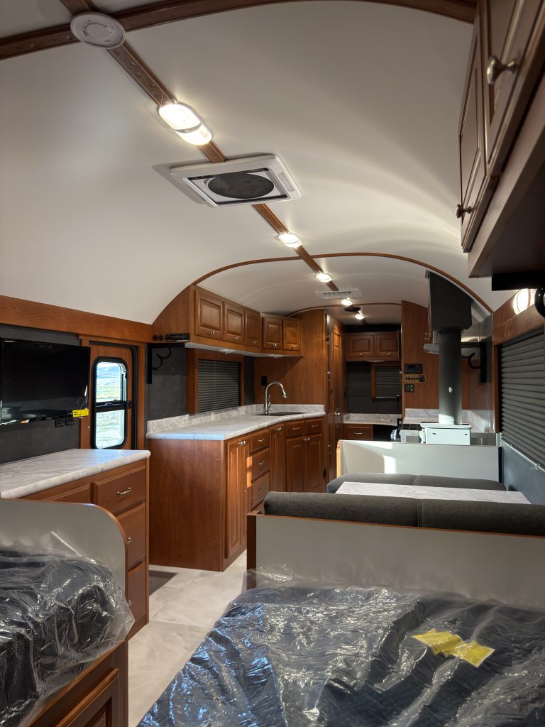 Wide view from the sleeping area toward the kitchen counter, dinette, and ceiling lights in Keulen Camp #132.