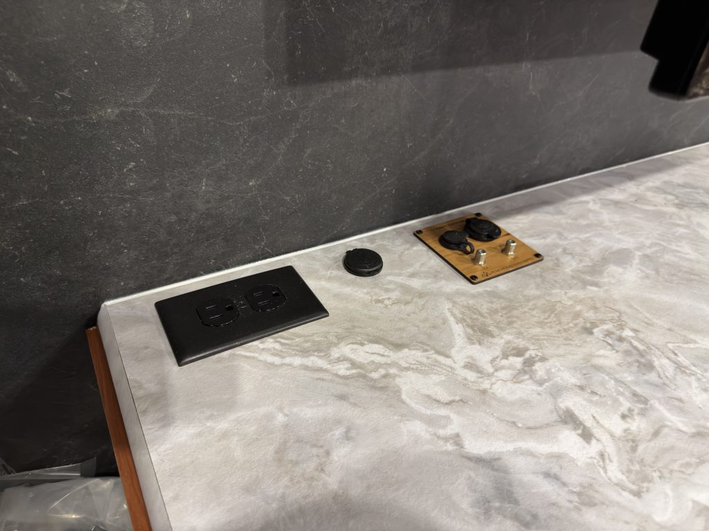 Power and USB outlets on the media center countertop beneath the television in Keulen Camp #132.