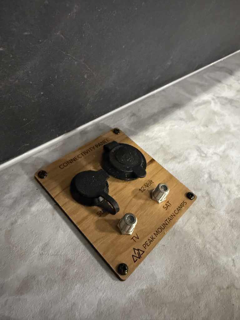 Close view of a brass connection panel with covered round ports in Keulen Camp #132.