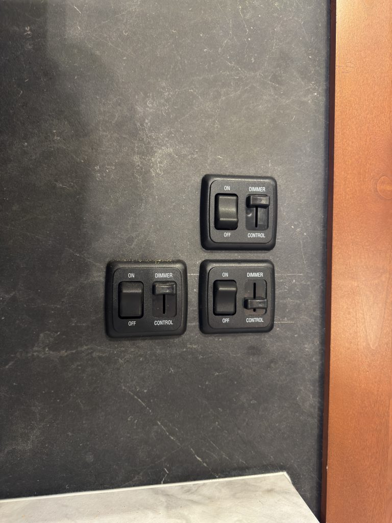 Interior and exterior light switch panels on the gray wall in Keulen Camp #132.