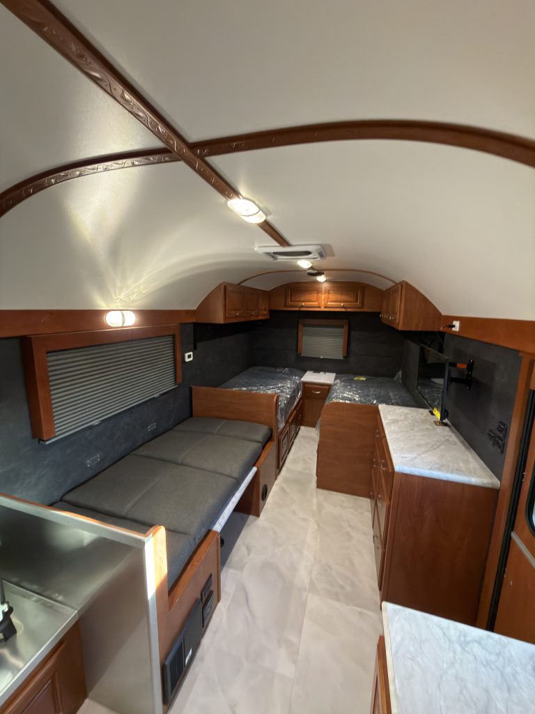 Converted dinette beside twin mattress platforms and central drawers in Keulen Camp #132.