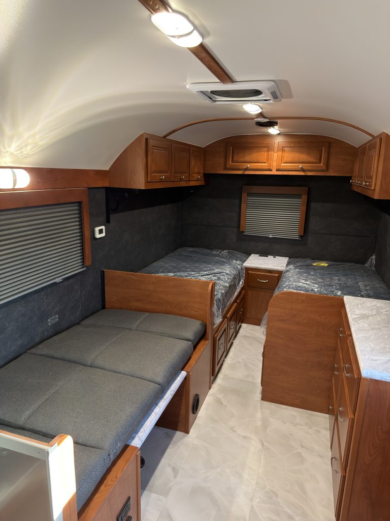 Sleeping area, converted dinette, overhead cabinets, and ceiling vent in Keulen Camp #132.