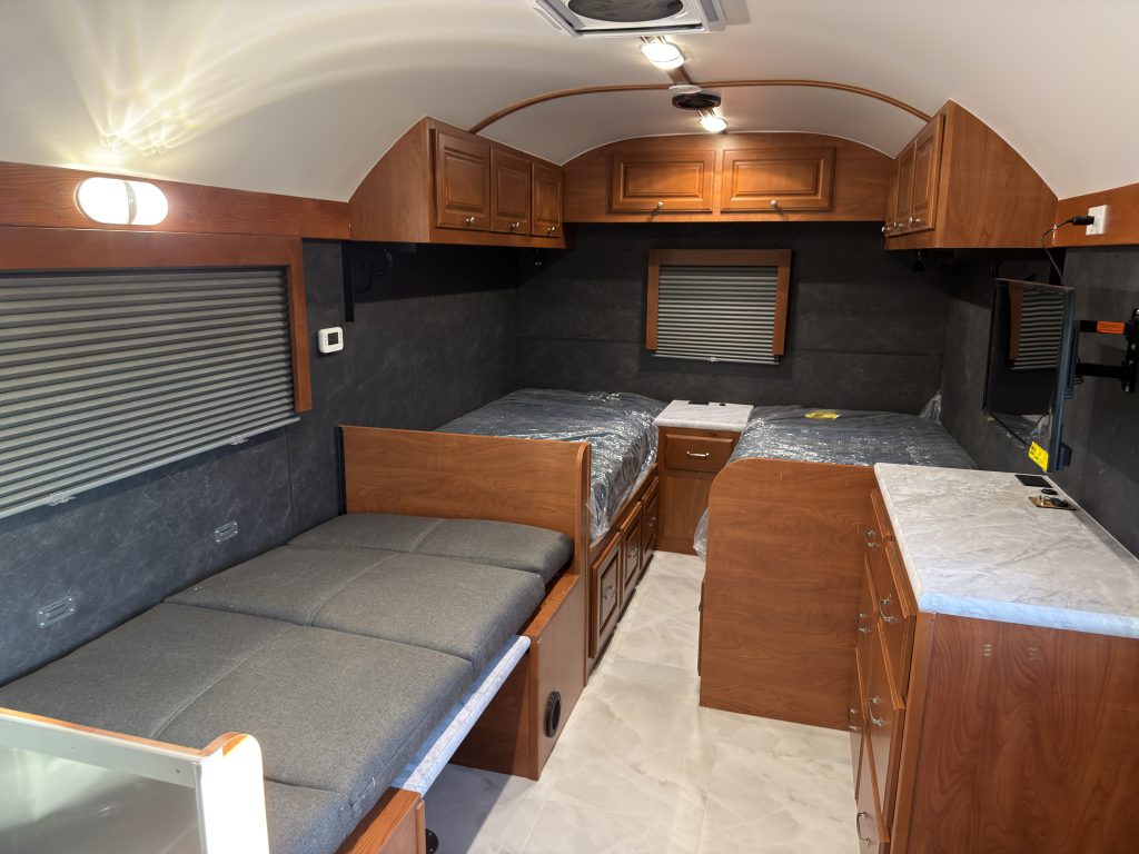 Closer view of the sleeping area, dinette, and open overhead cabinets in Keulen Camp #132.