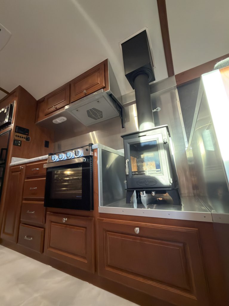 Kitchen range and wood stove beneath overhead cabinetry in Keulen Camp #132.