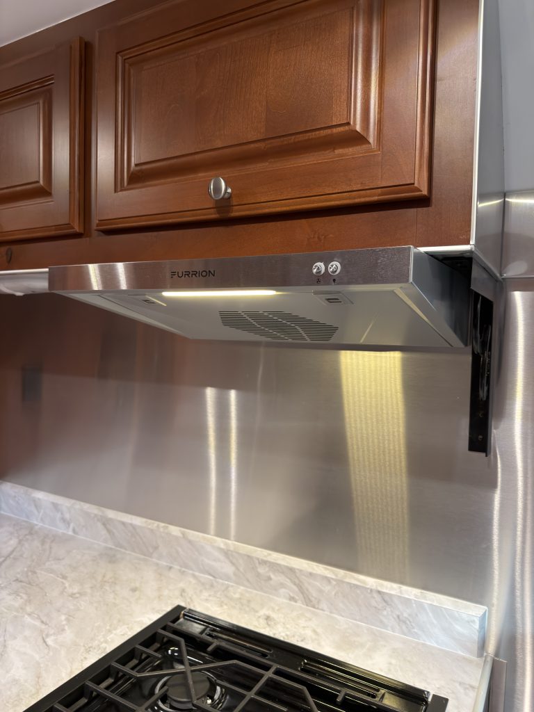 Range hood beneath a wood overhead cabinet in Keulen Camp #132.