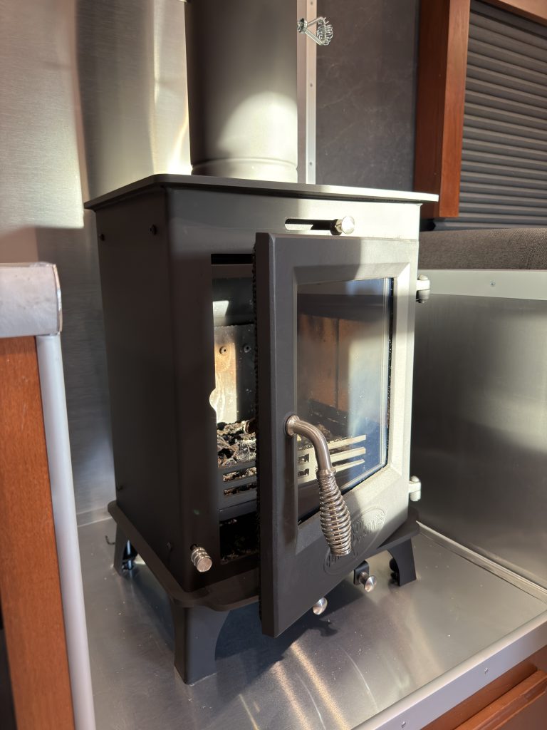 Close view of the black wood stove and flue in Keulen Camp #132.