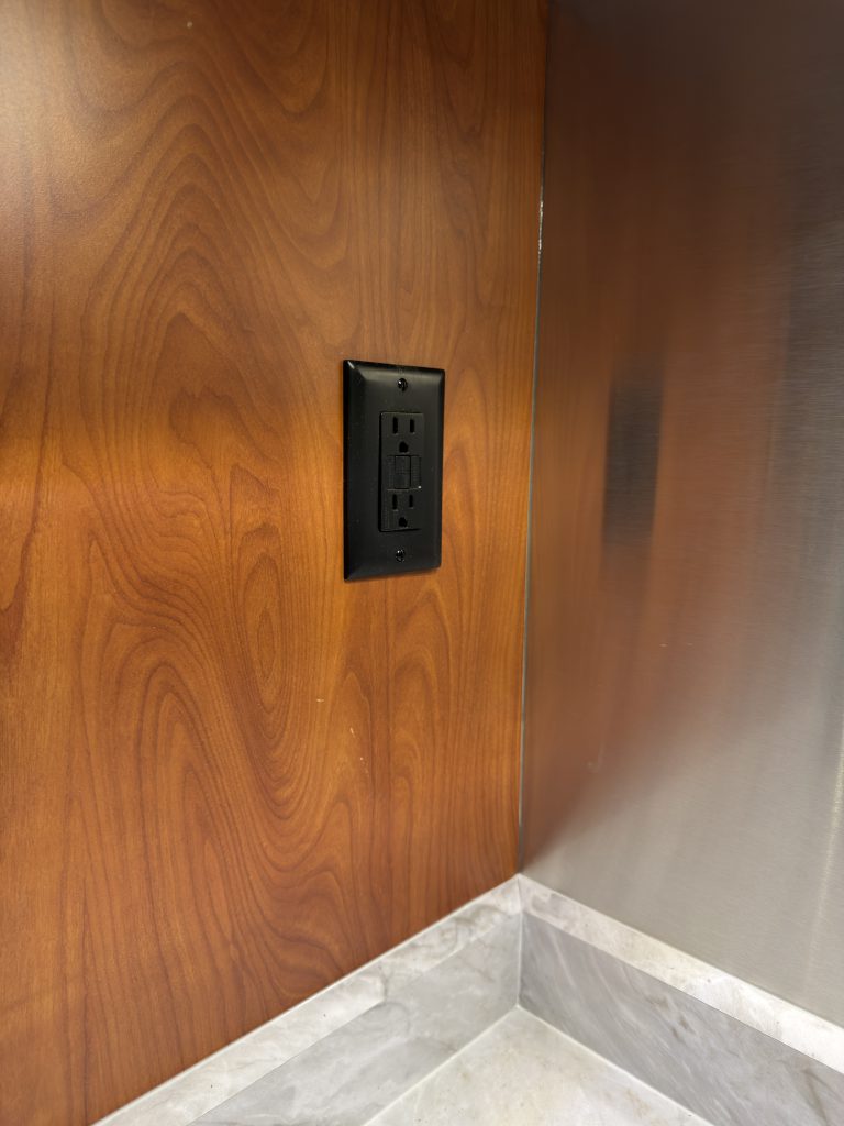 Black power outlet above the countertop in Keulen Camp #132.