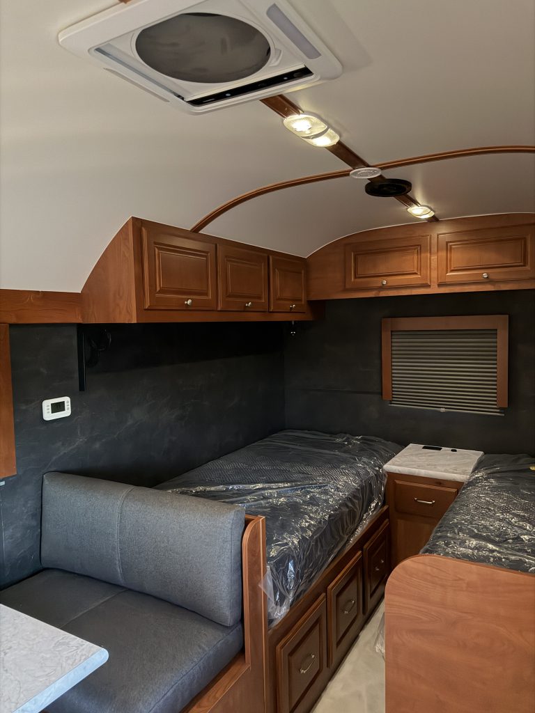 Twin mattress platforms and overhead cabinets beneath the Fantastic Fan in Keulen Camp #132.