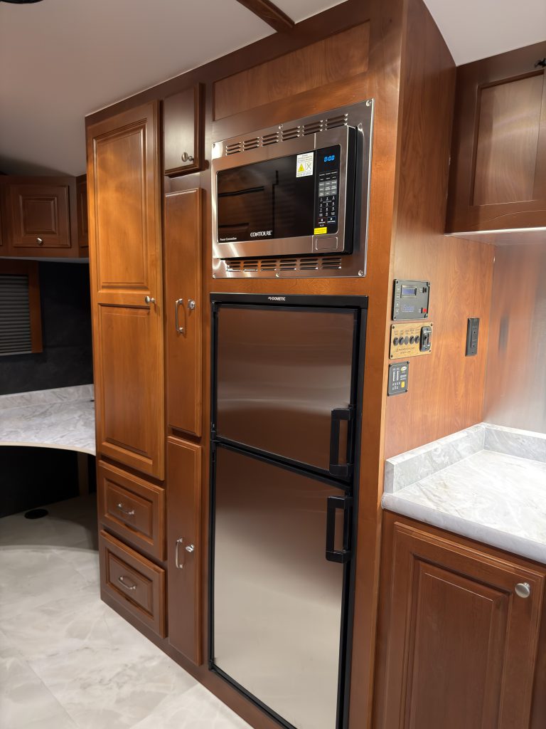 Stainless-front refrigerator with microwave above it in wood cabinetry in Keulen Camp #132.