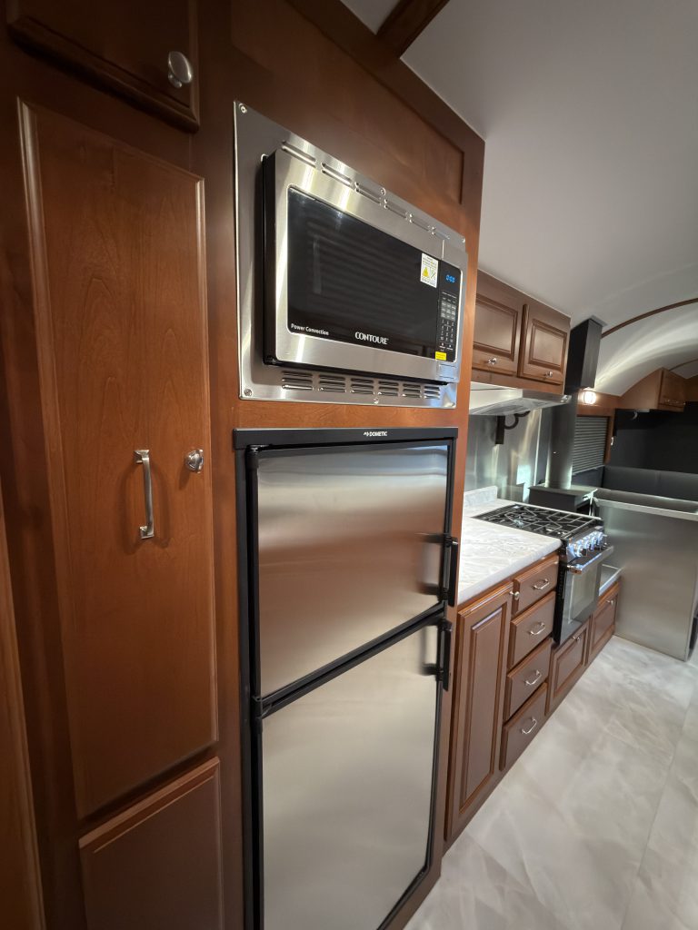 Microwave and refrigerator beside the kitchen counter in Keulen Camp #132.