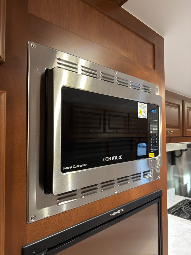 Stainless-trimmed microwave mounted above the refrigerator in Keulen Camp #132.