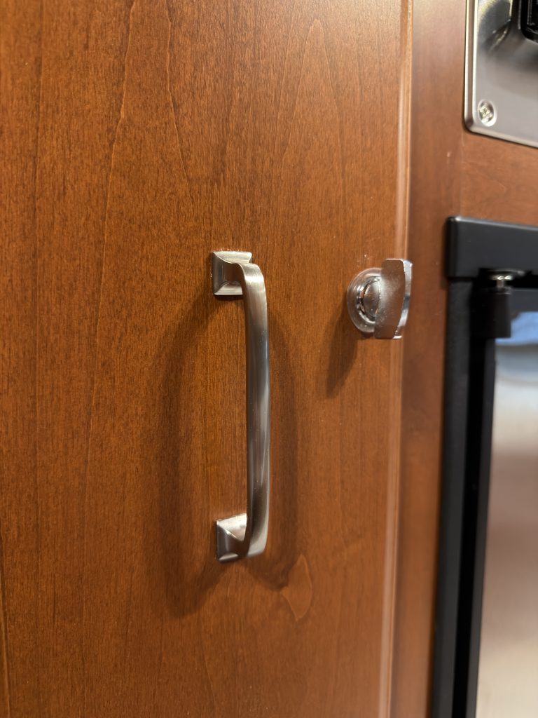 Metal pull handle and latch on a pull-out pantry in Keulen Camp #132.