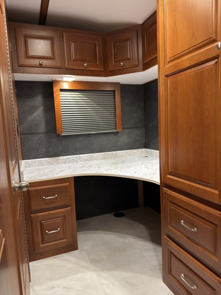 Corner office desk surrounded by wood cabinetry beneath a window in Keulen Camp #132.