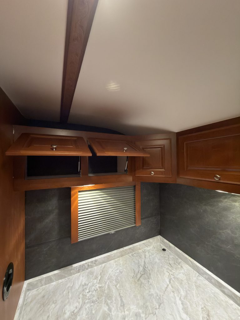 Open overhead cabinets above the corner office desk in Keulen Camp #132.