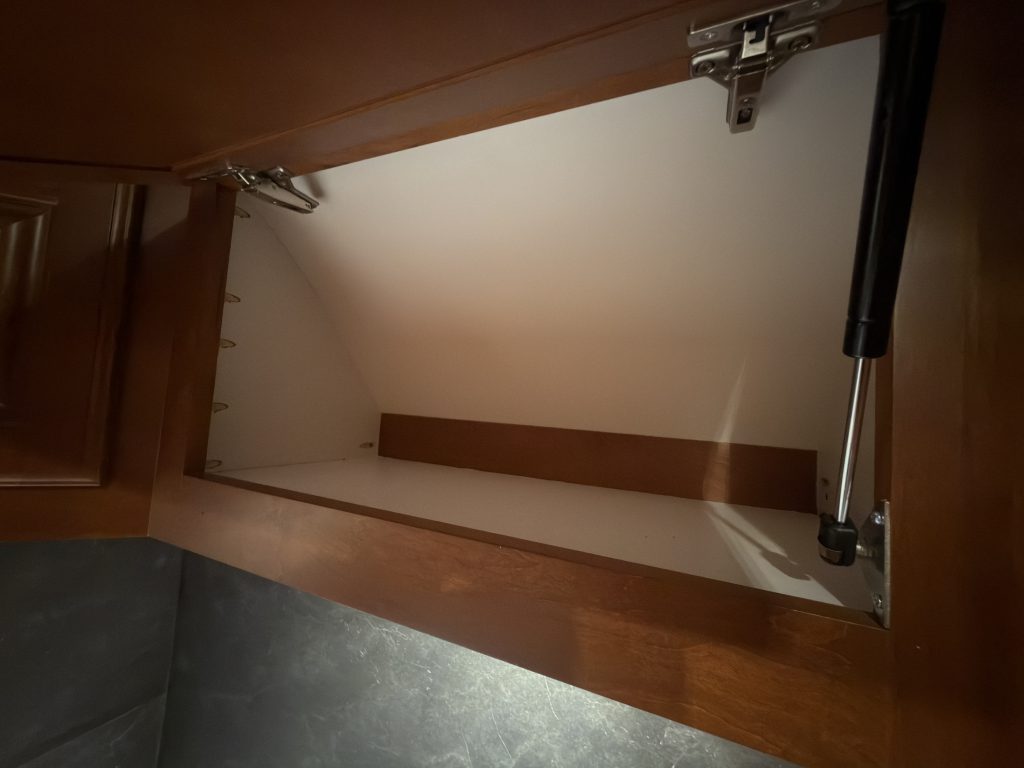 Lift support and hinges inside an overhead cabinet in Keulen Camp #132.