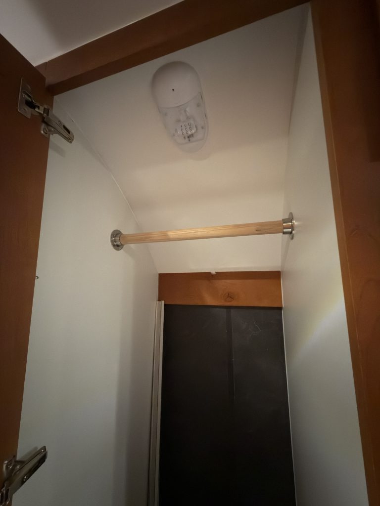 Tall open closet with hanging rail and upper light in Keulen Camp #132.