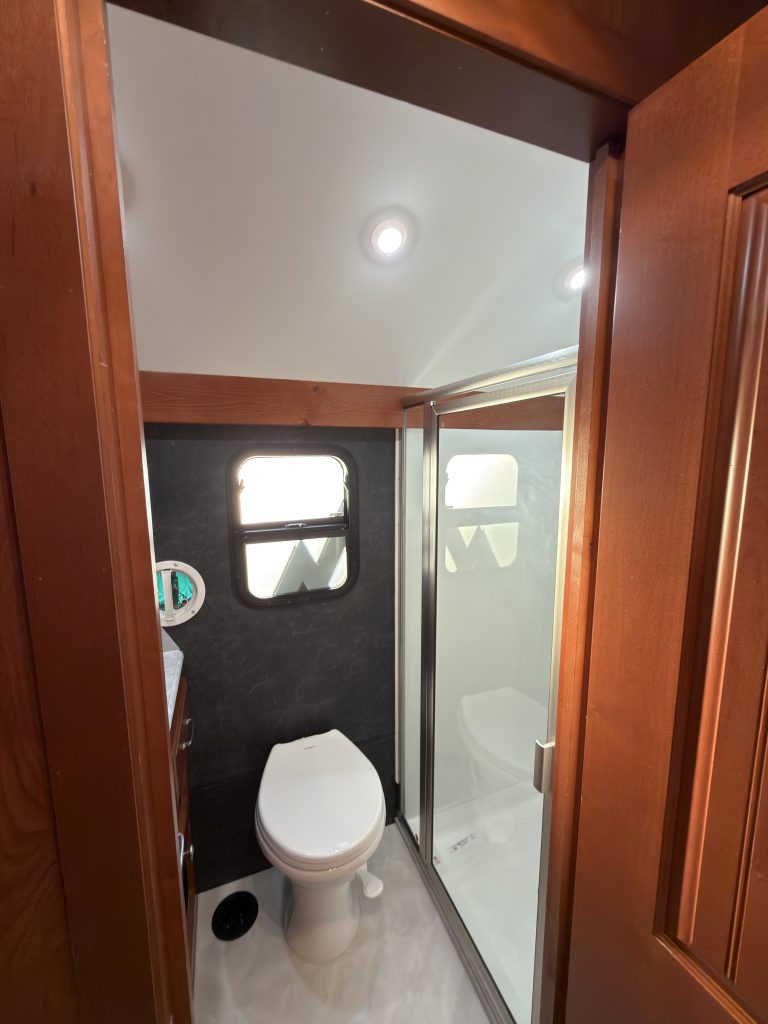 Bathroom viewed through the doorway with toilet, vanity, and glass shower in Keulen Camp #132.