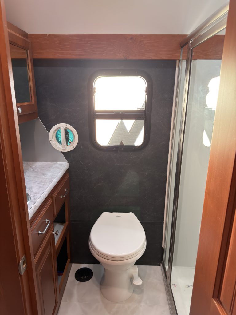Toilet beneath a small window beside the vanity in Keulen Camp #132.