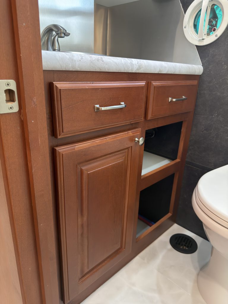 Wood vanity with drawers and lower storage beside the toilet in Keulen Camp #132.