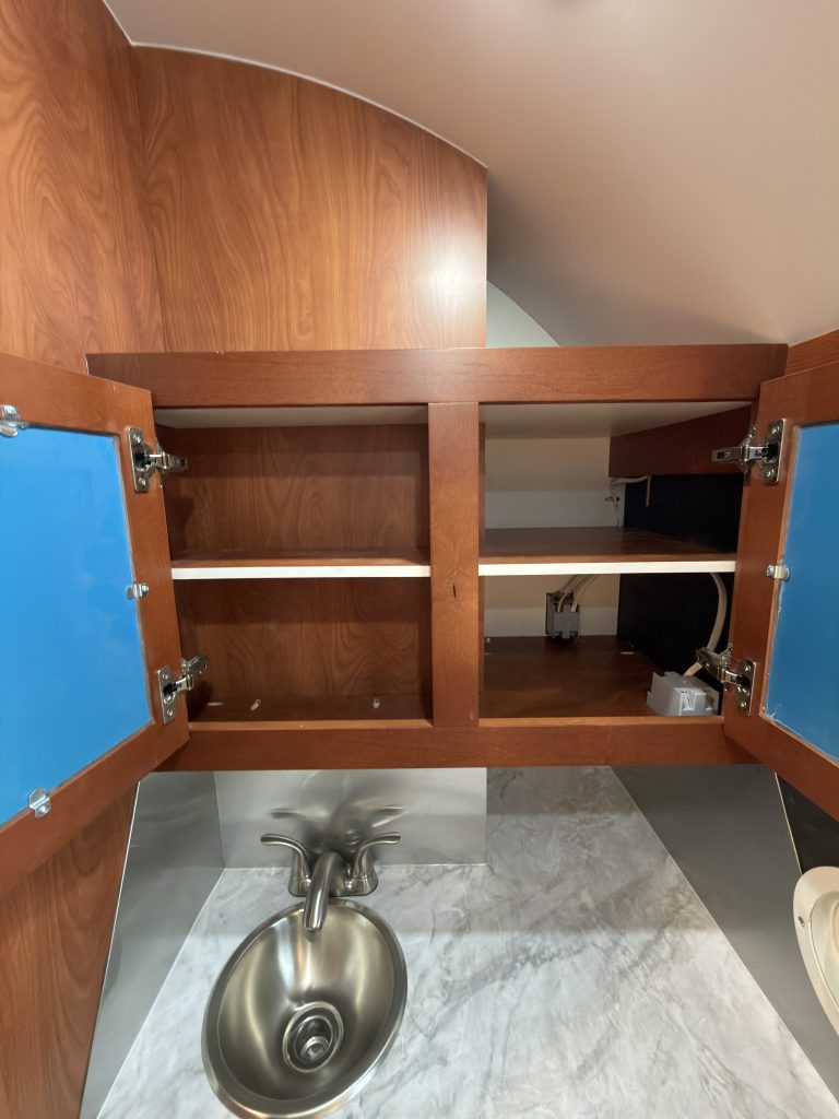 Mirrored cabinet doors open to reveal shelves in Keulen Camp #132.