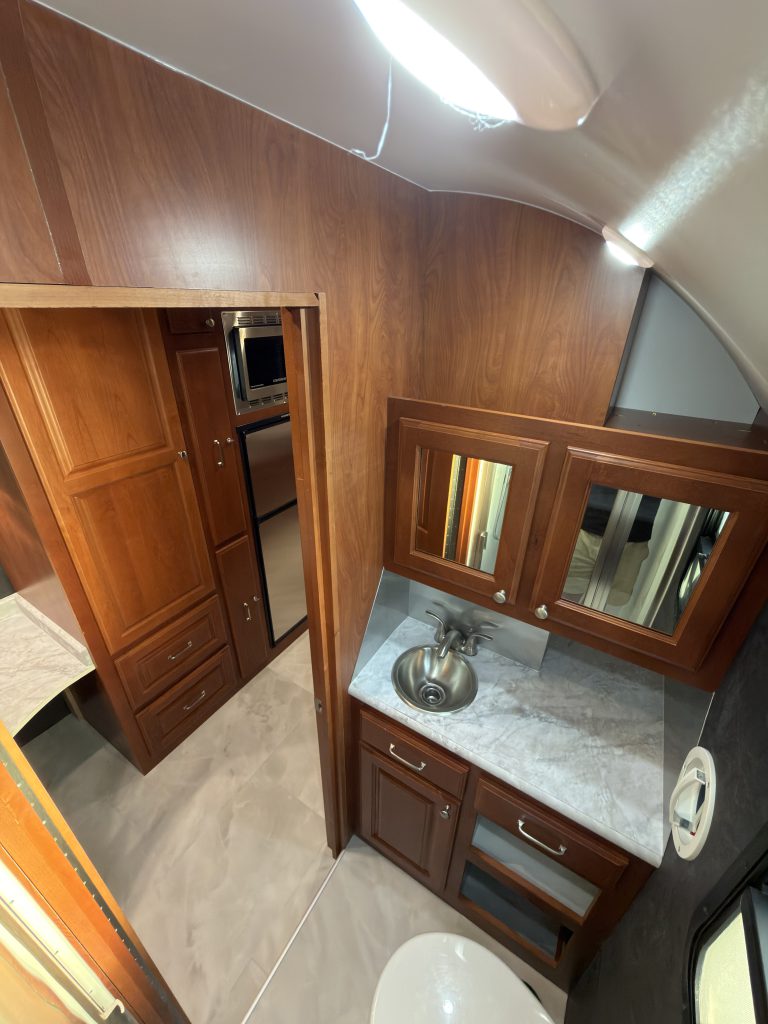 High view of the vanity, mirrored cabinets, and open doorway in Keulen Camp #132.
