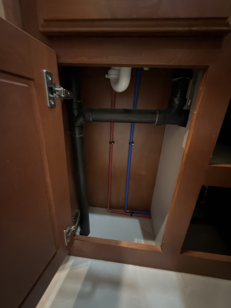 Close view of plumbing inside the bathroom vanity in Keulen Camp #132.