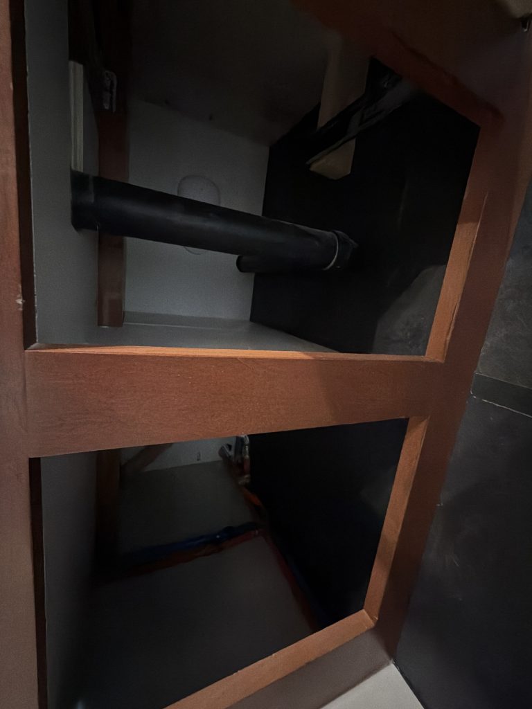 Open lower vanity compartments beside the toilet in Keulen Camp #132.