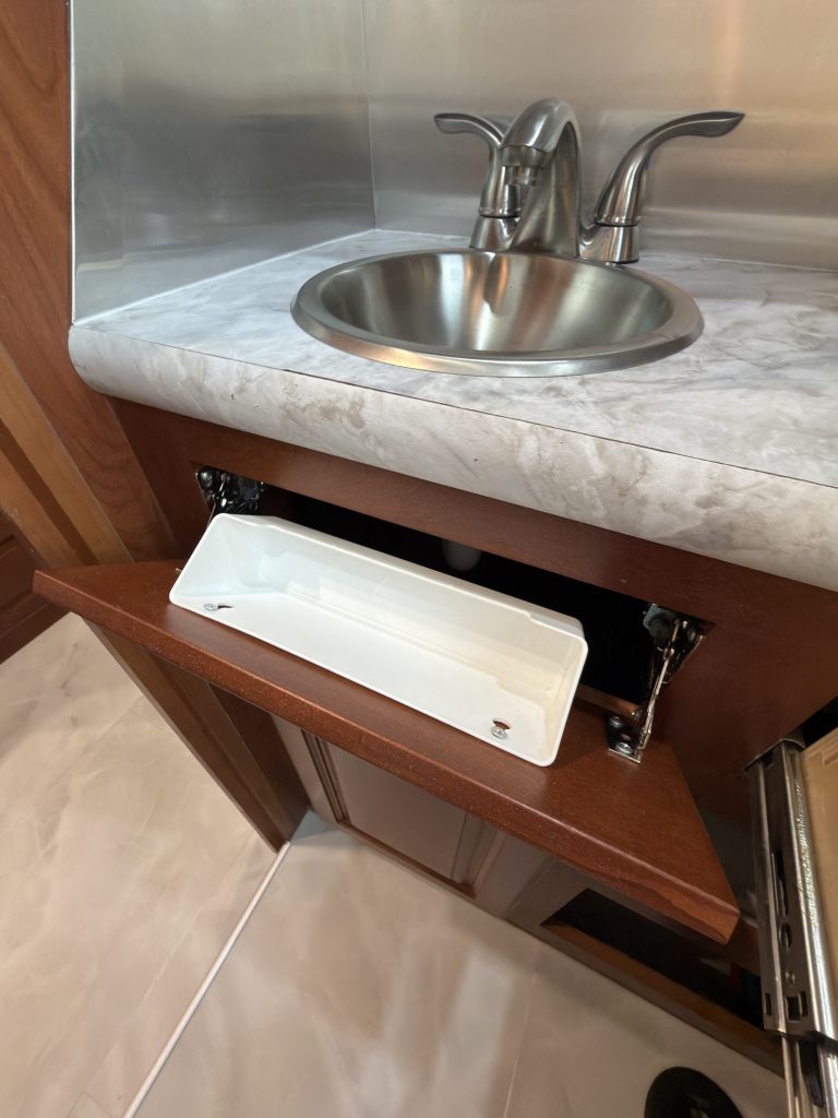 Tip-out storage compartment beneath the bathroom sink in Keulen Camp #132.