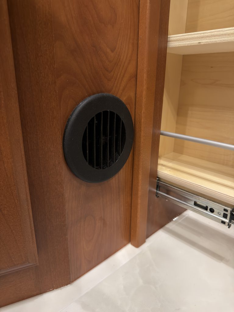 Round black ventilation grille in lower wood cabinetry in Keulen Camp #132.