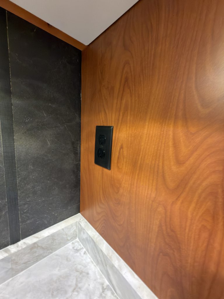 Black wall power outlet above the kitchen counter in Keulen Camp #132.