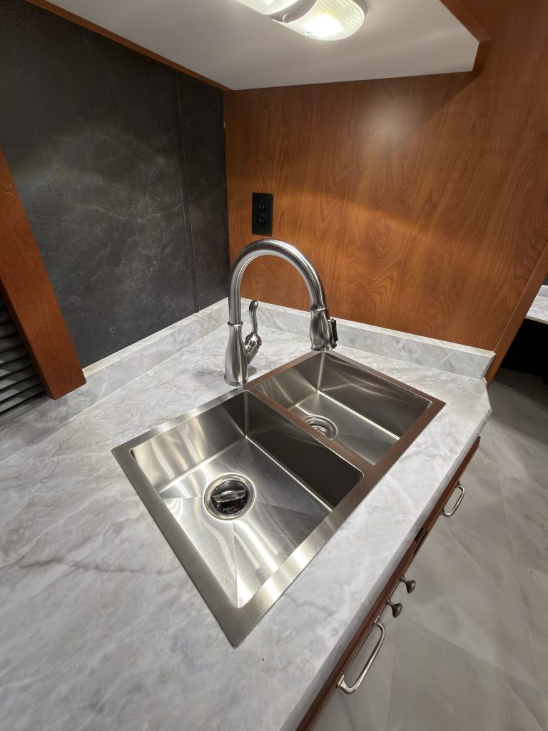 Double sink beneath a window and overhead cabinet light in Keulen Camp #132.