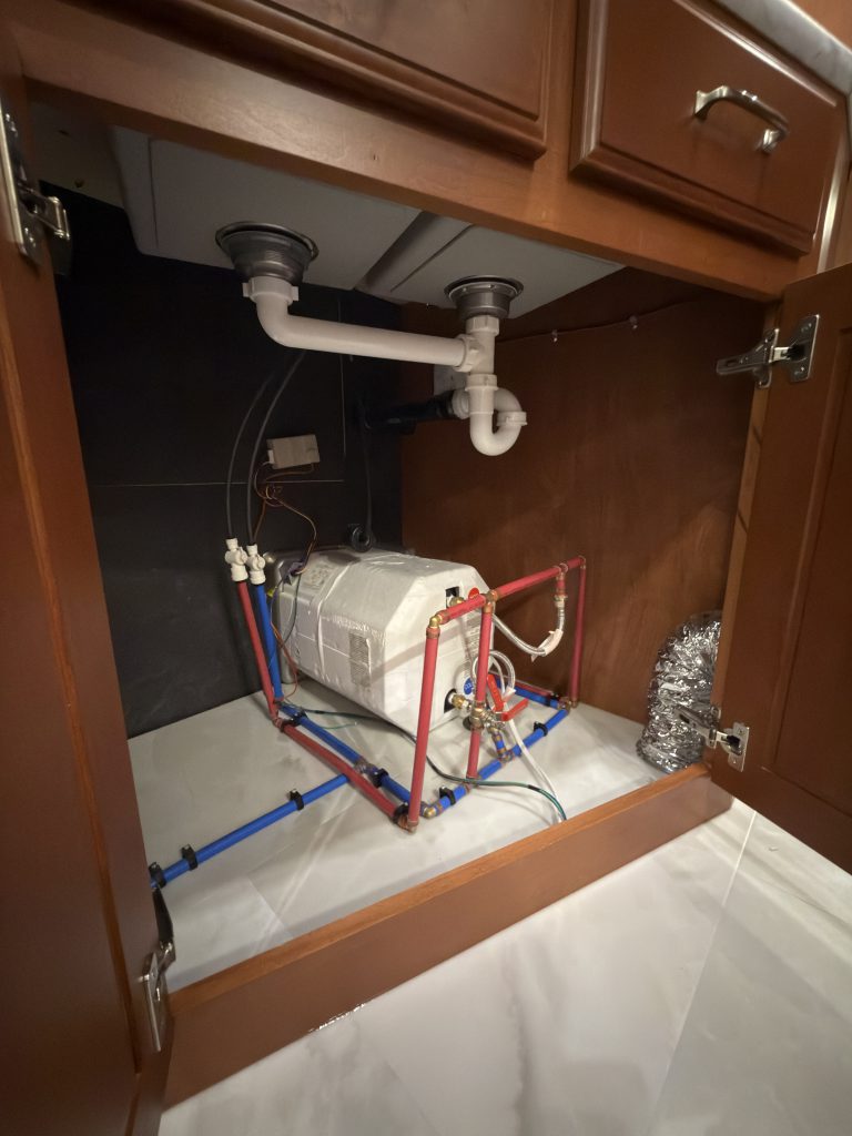 Sink drain pipes above equipment inside the lower cabinet in Keulen Camp #132.