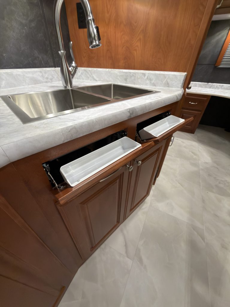 Tip-out storage compartments beneath the kitchen sink in Keulen Camp #132.