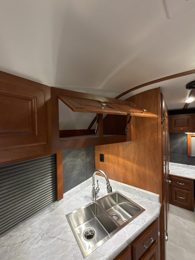 Open upper cabinet above the sink and window in Keulen Camp #132.