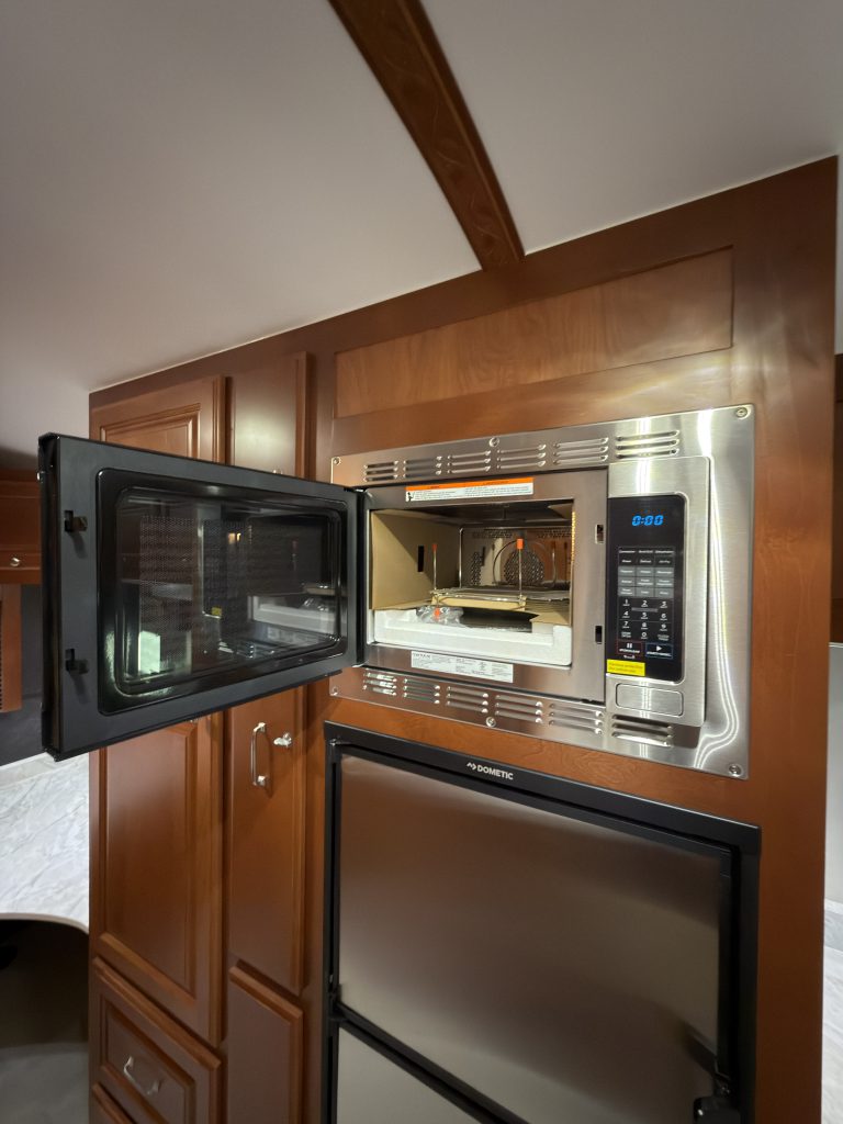 Open microwave above the stainless-front refrigerator in Keulen Camp #132.