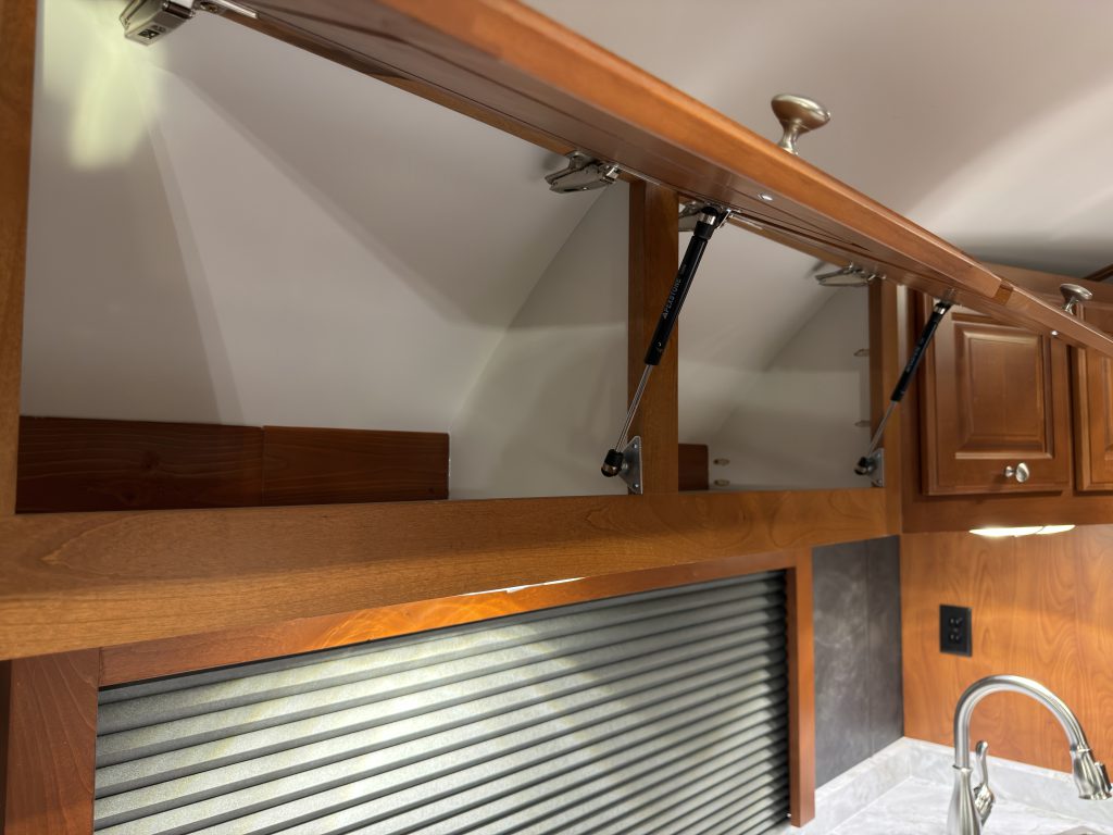 Lift supports inside an open overhead cabinet above a window in Keulen Camp #132.