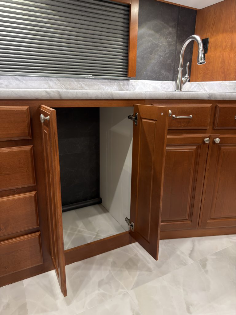 Empty lower cabinet with door open beneath the counter in Keulen Camp #132.