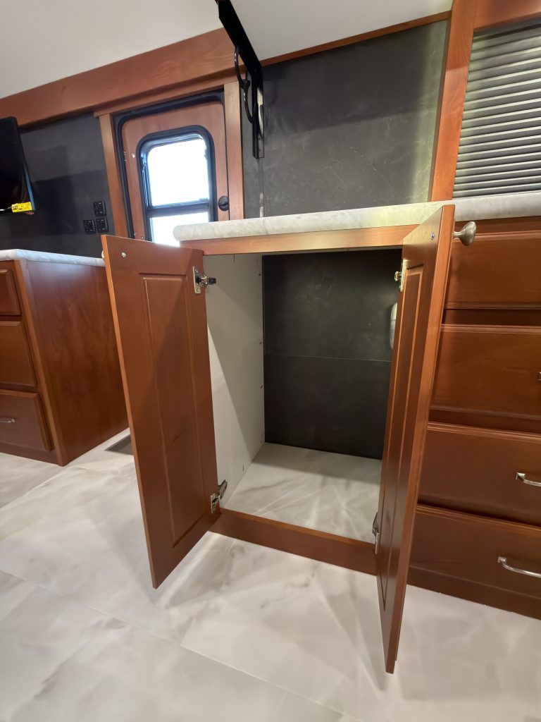 Open lower cabinet beside the entry door in Keulen Camp #132.