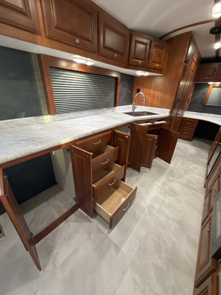 Wide view of open lower cabinets and drawers beneath the kitchen counter in Keulen Camp #132.