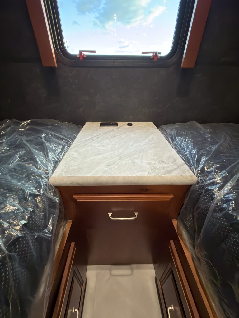 Central nightstand between the twin mattress platforms beneath a window in Keulen Camp #132.