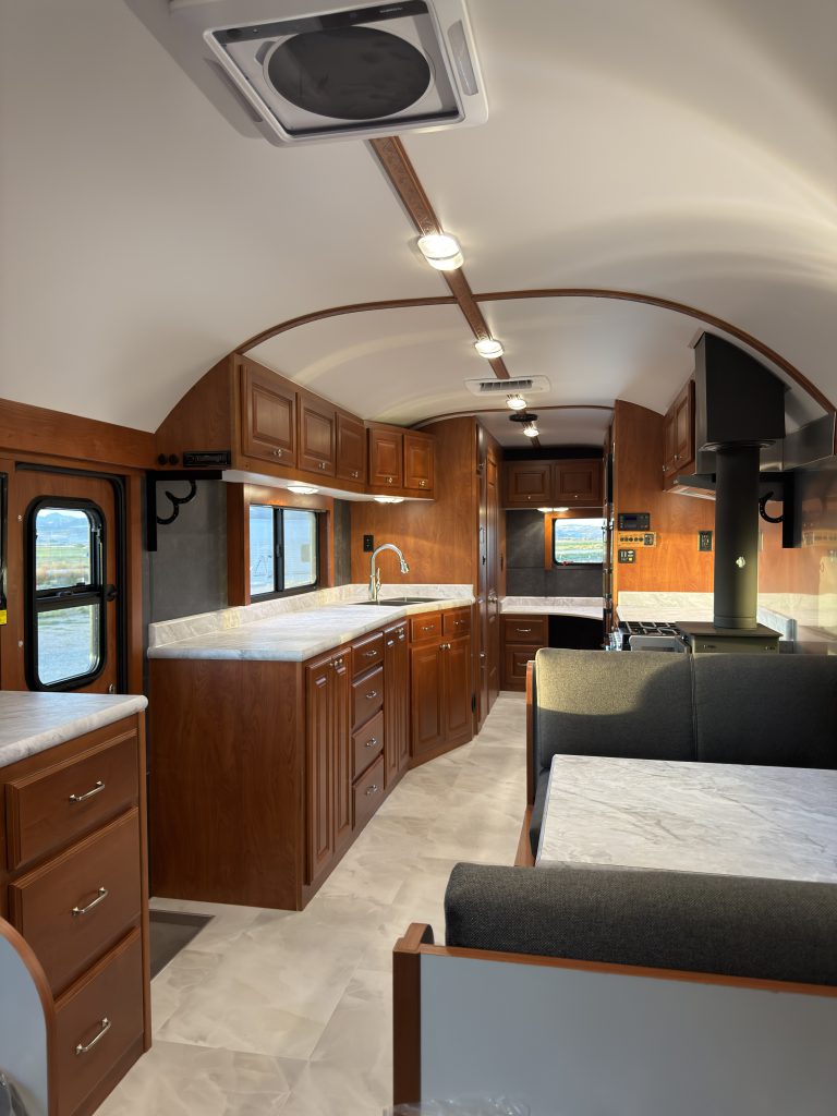 Wide cabin view of the kitchen, appliances, ceiling vent, and dinette in Keulen Camp #132.