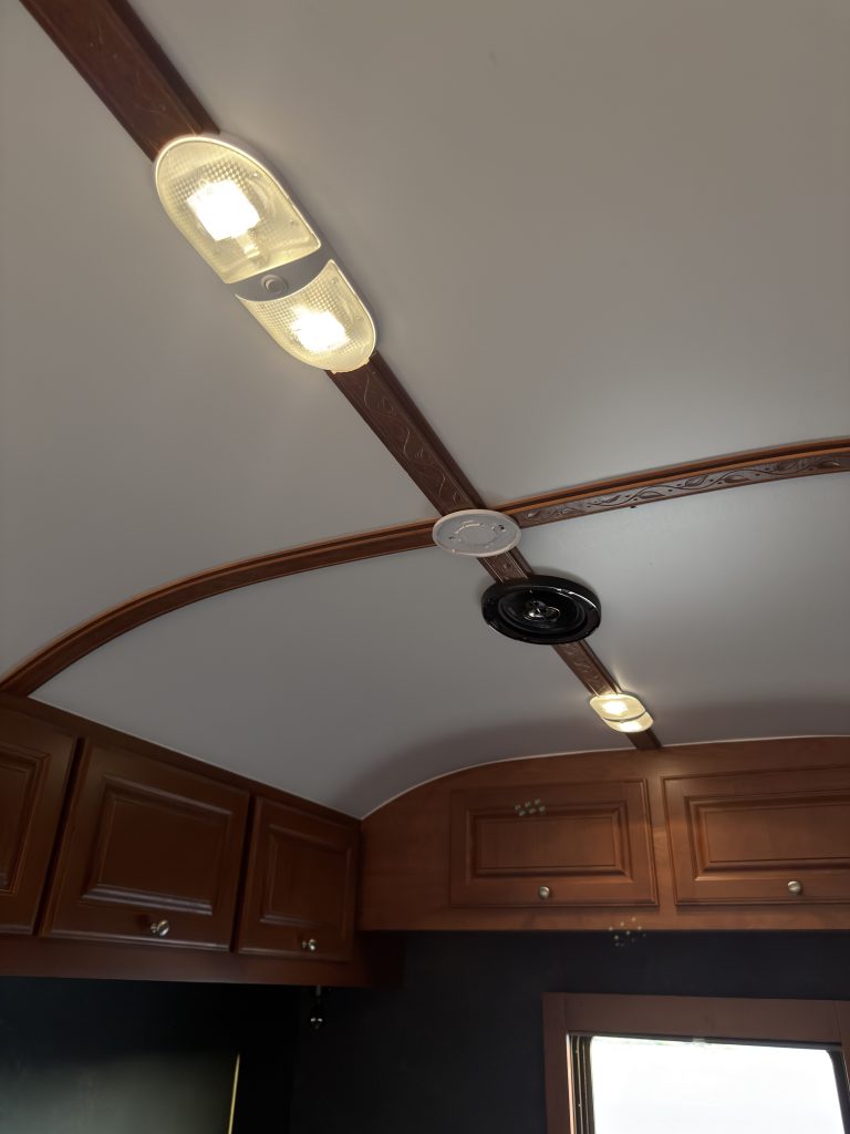 Ceiling light, curved wood trim, and speaker above overhead cabinets in Keulen Camp #132.