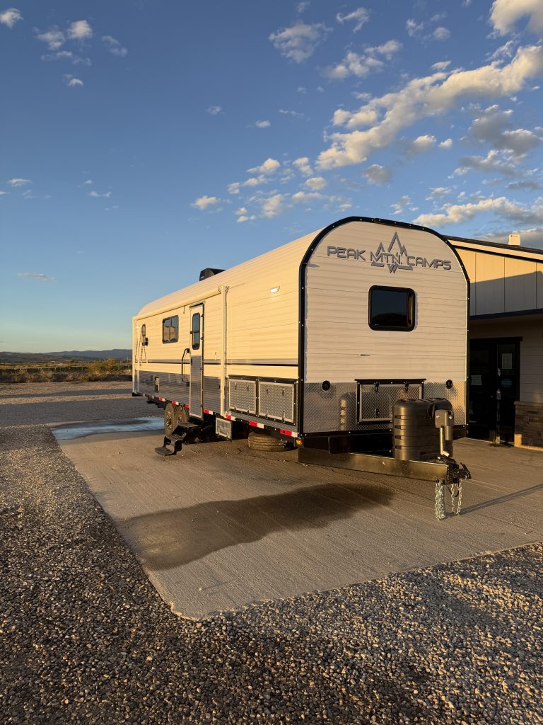 Wide front exterior with side windows and hitch in evening light in Keulen Camp #132.