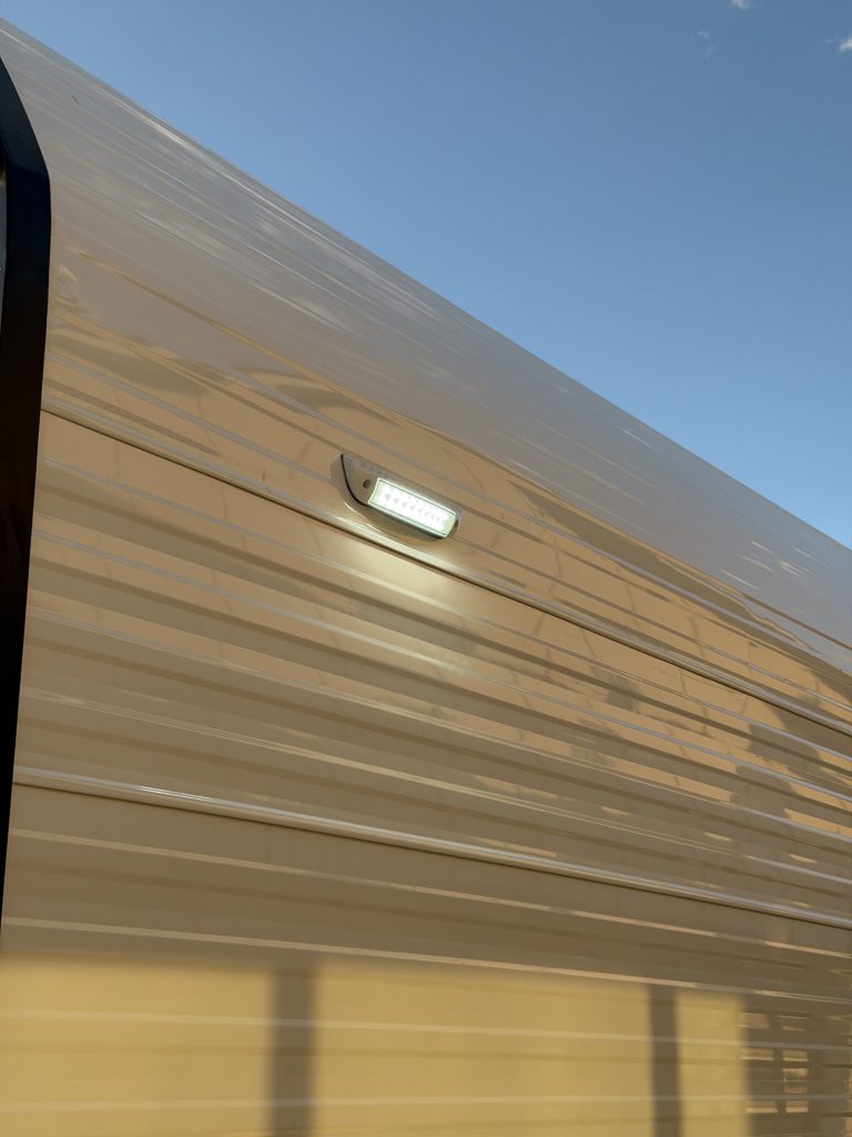 Illuminated rectangular exterior light on white siding in Keulen Camp #132.
