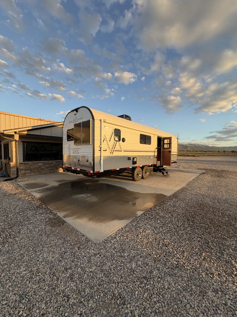 Wide entry-side exterior in warm light on a gravel lot in Keulen Camp #132.