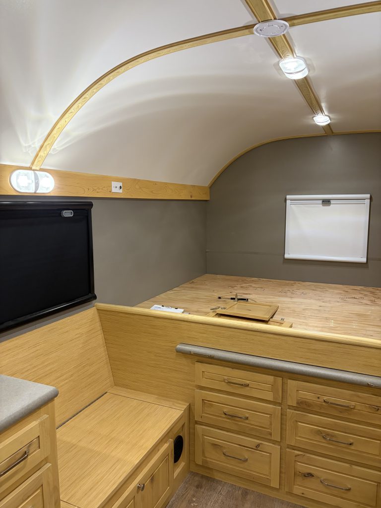 Van Niewkoop Camp #136: Raised east/west California king bed platform with built-in storage drawers and a rear window blind.