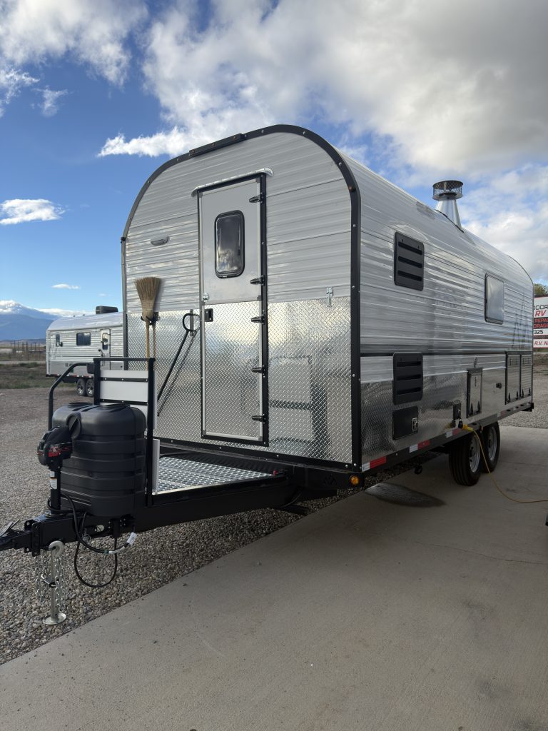Front entry-side view of the camp with its hitch and tandem axles in Van Niewkoop Camp #136.
